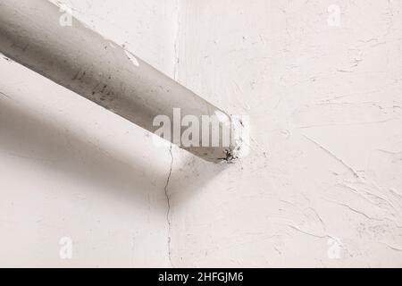 Old steel pipe heat house heating system in white plaster wall. Stock Photo