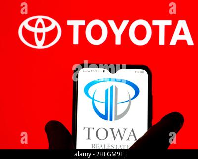 In this photo illustration, the Towa Real Estate logo is seen displayed on a smartphone screen with the Toyota logo in the background. Stock Photo