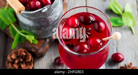 Fresh cranberry juice with cinnamon and anise in glass jars on the old wooden background. Selective focus.Top view. Stock Photo