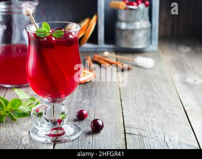 Fresh cranberry juice with cinnamon and anise in glass jars on the old wooden background. Selective focus. Stock Photo