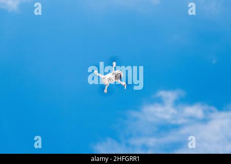 Little drone flying in blue sky. Shooting video from a quadcopter. Copy space. Stock Photo