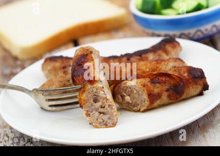 Crispy, fried British pork sausage on fork, closeup Stock Photo