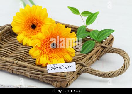 Thank you card with two yellow gerbera daisies on wicker tray Stock Photo