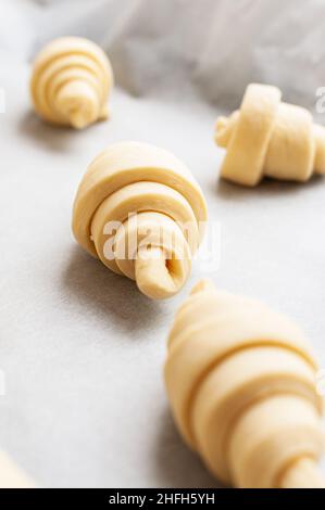 Semifinished or unbaked croissant on a baking sheet. Puff pastry baking. Close up. Stock Photo