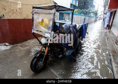 Palestinians on a street flooded by heavy rain during a depression in the city of Rafah in the southern Gaza Strip, on January 16, 2022. Stock Photo