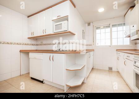 A small kitchen with stainless steel appliances, white cabinets, and a  natural light colored wood counter top Stock Photo - Alamy