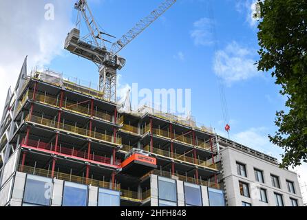 London, England - June 2020: Tower crane working on the side of a tall new building under construction Stock Photo