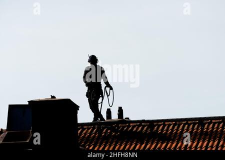 Gothenburg, Sweden - May 06 2020: Silhouette of a chimney sweeper on top of a roof Stock Photo