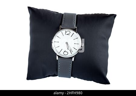 classic wristwatch with round dial in silver and minimalist design with leather strap unisex accessory put on a black pillow for demonstration, object Stock Photo