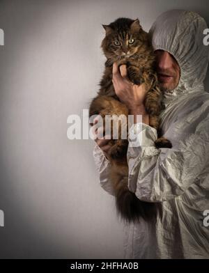 Man with white protection suit and tabby cat near old brick wall Stock Photo