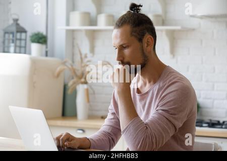 Pensive young hipster man working on computer. Stock Photo