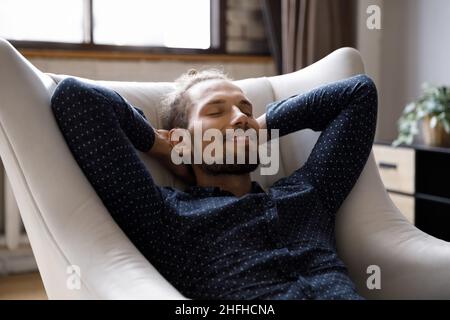 Smiling sincere handsome young man resting at home. Stock Photo