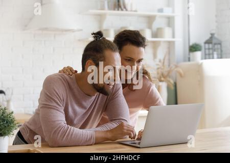 Smiling bonding young family couple using computer. Stock Photo