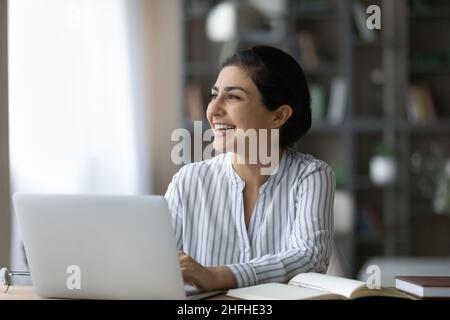 Happy millennial Indian woman working in modern office. Stock Photo