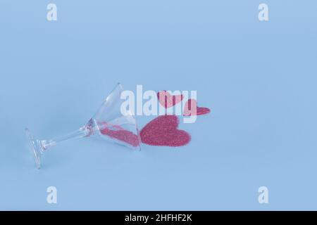 Spilled cocktail glass with pink glitter in the shape of a heart. Creative idea. Minimal Valentine's day party, love concept. Stock Photo