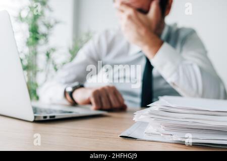 Career failure, disappointed businessman covering face in office while sitting at the desk, selective focus Stock Photo