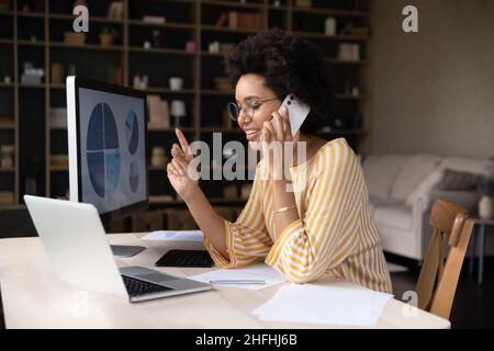 Focused smiling young African American businesswoman multitasking. Stock Photo