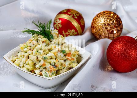 Classic New Year's table with traditional salad and christmas decorations on a white tablecloth. Russian dishes for New Year. Olivier salad. Stock Photo