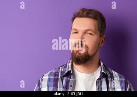 Happy bearded man in shirt smiling looking at camera on purple background. Young handsome stylish guy Stock Photo