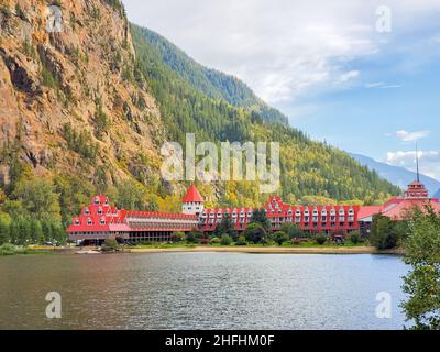 Beautiful landscape of a mountain and lake with red buildings on a shore. Three Valley Gap Lake Chateau Hotel, BC, Canada-September 26,2021. Stock Photo