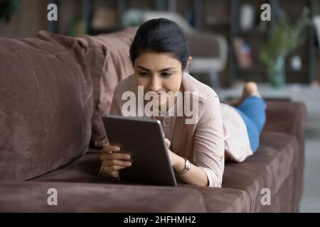 Cheerful young Indian woman using digital computer tablet. Stock Photo