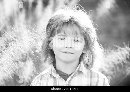 Closeup attractive boy outdoor. Portrait of young smiling child. Kids emotions concept. Blur background.