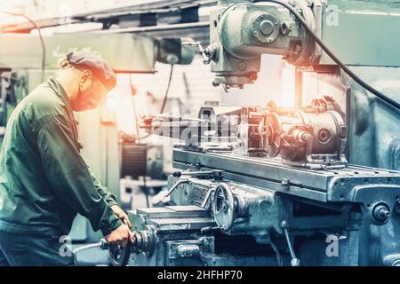 Factory worker using grinder machine tool in metal work factory workshop. Heavy industry manufacturing concept. Stock Photo