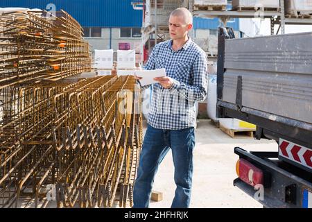 Man worker with papers collecting order at warehouse Stock Photo