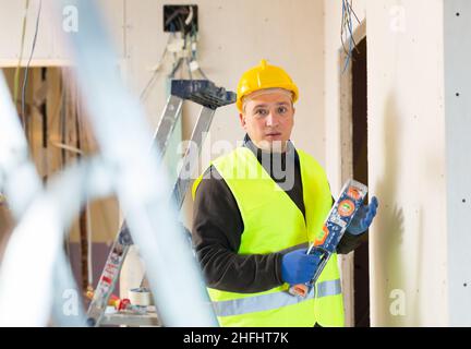 Builder checks the vertical of the wall using level Stock Photo