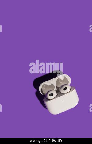 Barcelona, Spain - January 2022. New airpods pro in wireless charging case on violet background. Headphones, vertical photo, copy space. Music Stock Photo