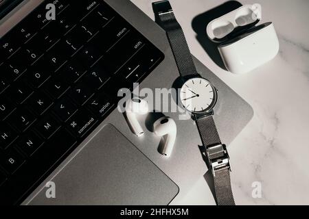 Barcelona, Spain - January 2022. New airpods pro on apple laptop. Wireless compact headphones. Music, watch, technology, electronics concept. Stylish Stock Photo