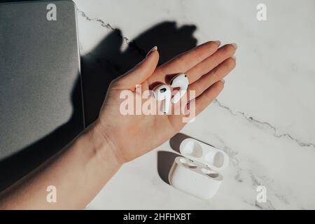 Barcelona, Spain - January 2022. New airpods pro in female hand. Wireless compact headphones. Music, watch, technology, electronics concept.  Stock Photo