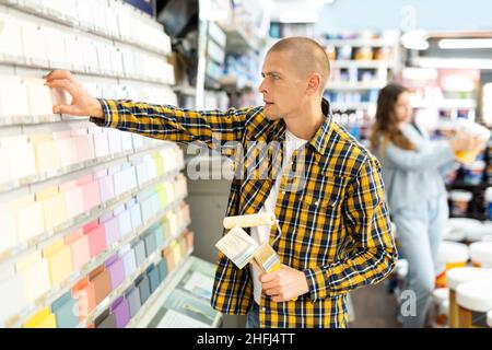 Young male customer choosing paint color for renovation works Stock Photo