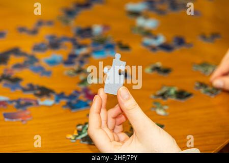 Person holding puzzle piece while working a jigsaw pizzle Stock Photo