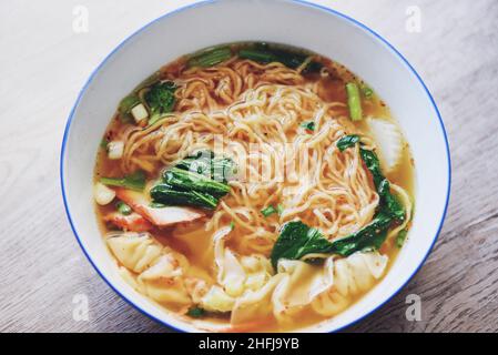 soup noodle wonton pork yellow noodle with red roasted pork dumpling and bog choy chinese vegetable in soup bowl on wooden table, top view Stock Photo