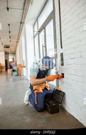 Electrician fixing power electric socket with screwdriver Stock Photo