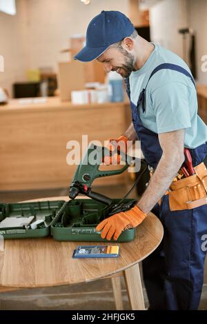 Cheerful male builder holding electric hammer drill Stock Photo