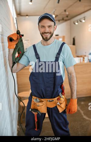 Cheerful male worker holding electric hammer drill Stock Photo