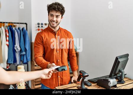 Customer hand paying to shopkeeper man using credit card at clothing store. Stock Photo