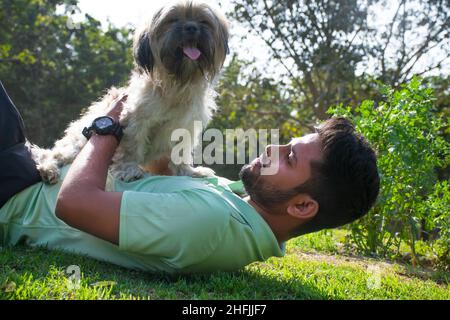 young man playing fetch with his Dog in the park Stock Photo