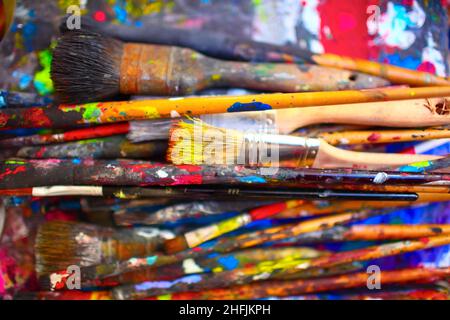 Paint brushes of different sizes, stained by vivid colors, close-up. Stock Photo