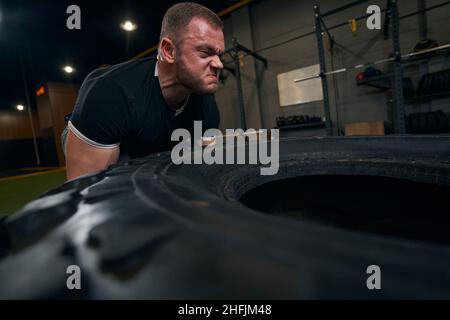 Focused strong Caucasian sportsman doing tire training Stock Photo