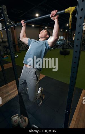 Focused calm young male gymnast doing pull-ups Stock Photo
