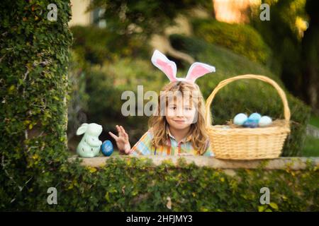 Easter bunny child hunting eggs with easters basket outdoors on Happy Easter day. Stock Photo