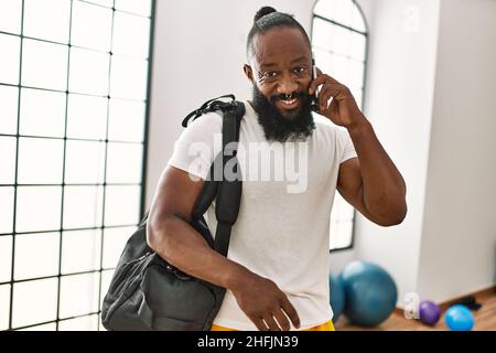 Young african american man holding gym bag talking on the smartphone at sport center Stock Photo