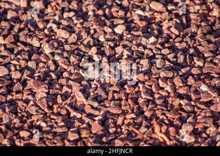 Red decorative granite crushed stone of a small fraction, a background on the theme of building materials with a depth of field. Bulk material road su Stock Photo