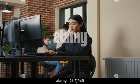 Portrait of focused system engineer happy with parsing results sitting at desk in software development office. Programer writing algorithm smiling after successfuly compiling source code. Stock Photo