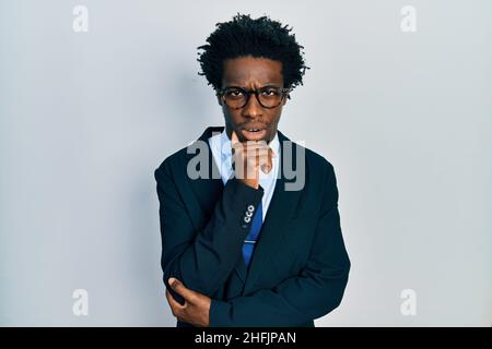 Young african american man wearing business suit and tie in shock face, looking skeptical and sarcastic, surprised with open mouth Stock Photo