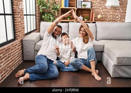 Family of three doing house shape with arms smiling happy pointing with hand and finger to the side Stock Photo