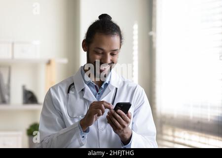 Smiling young African American doctor using cellphone. Stock Photo